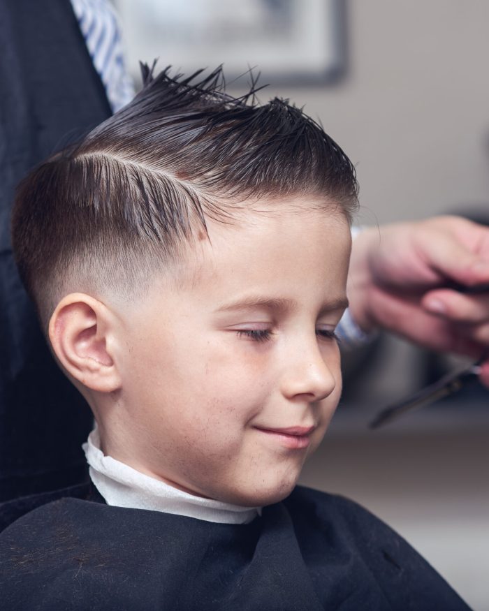 Barber,Is,Cutting,A,Hair,To,Caucasian,Boy,In,Barbershop.